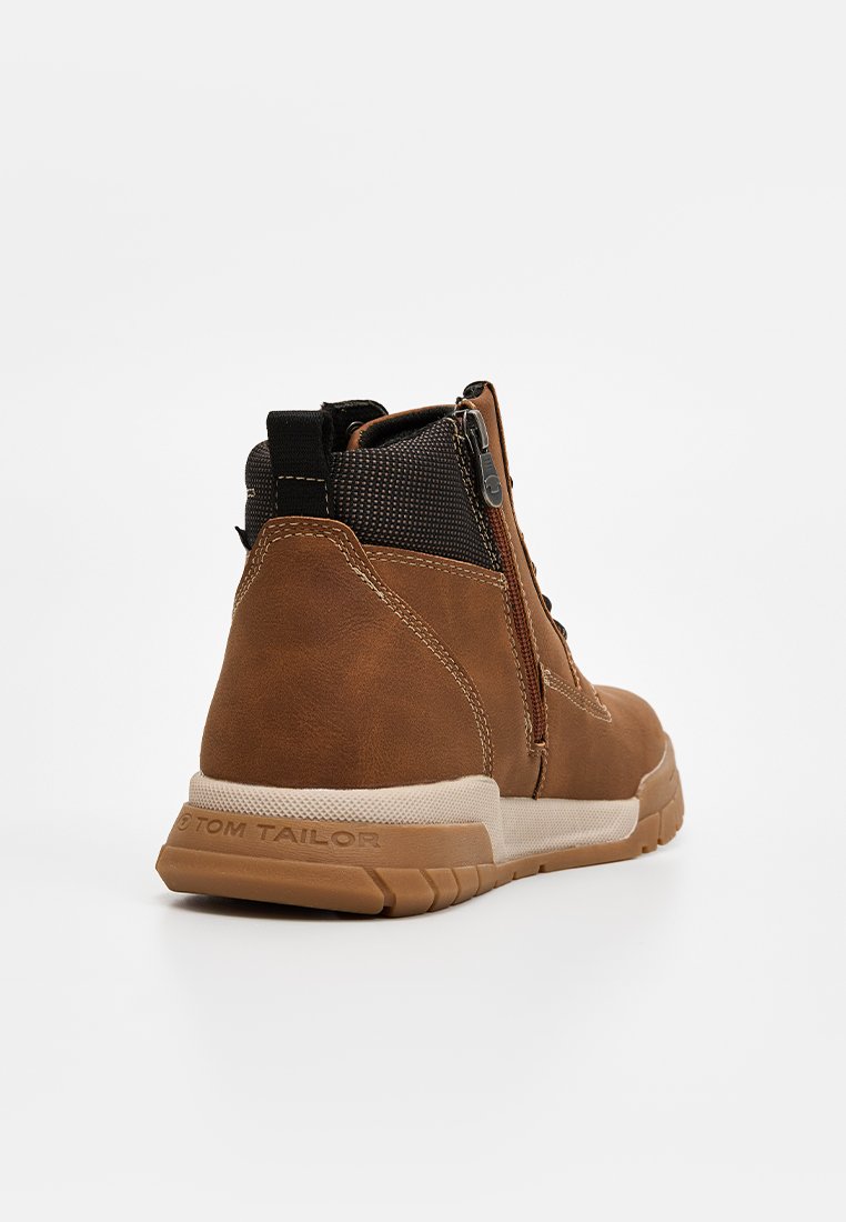 Botas altas marrones de ante con un panel de malla texturizado, que cuentan con un zipper lateral y una suela de goma con un acento blanco que contrasta.