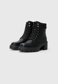 Bottines noires avec un talon épais, un laçage sur le devant, des œillets dorés, une semelle en caoutchouc et un revers en tissu en haut. Texture en cuir lisse.