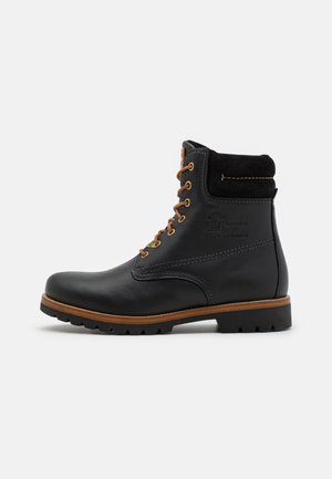 Černá kožená kotníková bota s hnědými tkaničkami, polstrovaným límcem, robustní podrážkou a vytlačeným logem na boku, zobrazená z vnější strany.