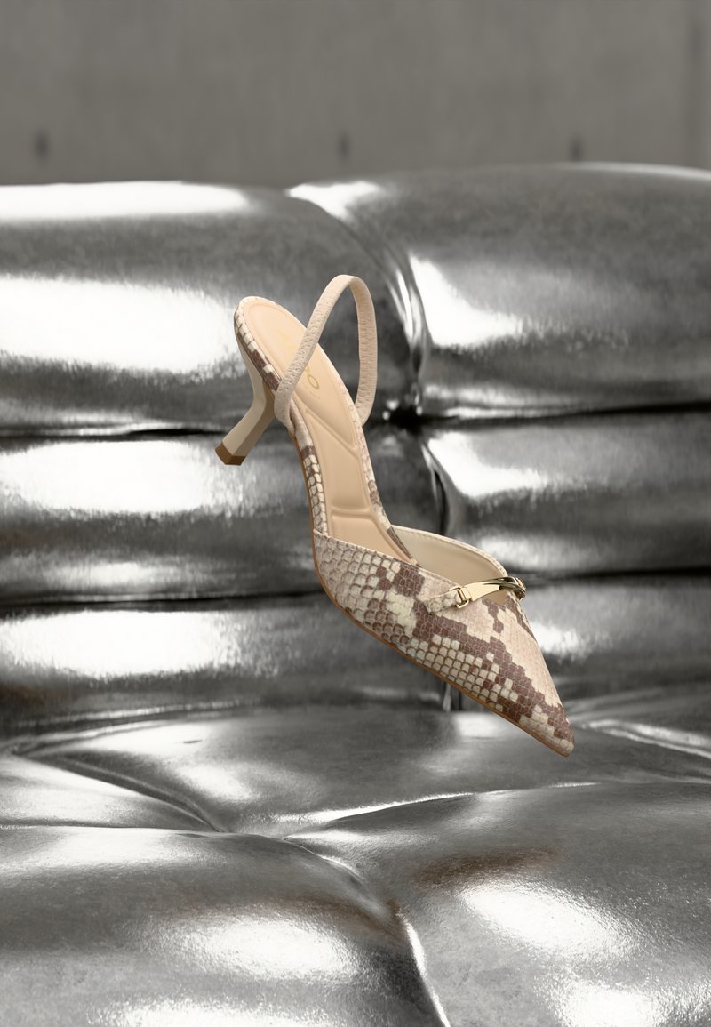 Escarpin à bout pointu avec bride arrière en cuir imprimé serpent beige, doté d'un accent doré et d'un talon fin, présenté sur une surface argentée brillante.