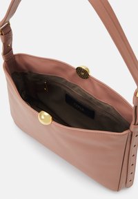 Sac à main en cuir rose au toucher lisse, avec des équipements en or et un intérieur spacieux comprenant une poche zippée et une étiquette de logo.