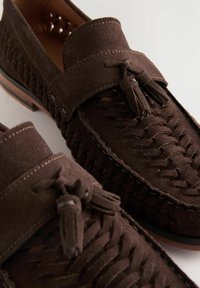 Brune ruskinds loafers med vævet design og kvastdetalje, kontrasterende syninger og gummisål for holdbarhed og greb.