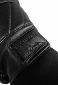 Schwarze Lederhandschuhe mit einem gesteppten Design, genähten Akzenten und einem strukturierten Patch mit Berggrafiken und Branding.