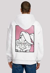 Felpa bianca con cappuccio caratterizzata da una grande grafica contornata di un personaggio dei cartoni su uno sfondo rosa. Il materiale sembra morbido, con una vestibilità comoda.