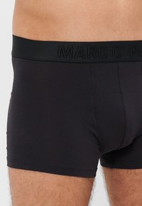 Svarte bomullboxershorts med en elastisk midjebånd med merket "MARC O'POLO" preget. Glatt tekstur med en tett passform.