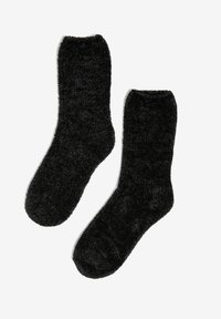 Czarne, puszyste skarpetki o miękkiej fakturze, do kostki, z zaokrąglonymi palcami i prążkowanym mankietem. Materiał wydaje się ciepły i przytulny. Bez wzorów ani akcentów.