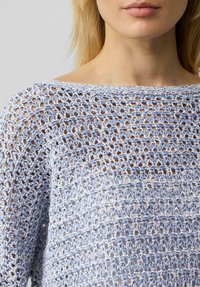 Hellblauer Strickpullover mit offenem Häkelmuster, weitem Halsausschnitt und langen Ärmeln mit einer feinen, strukturierten Oberfläche.