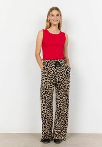 Červený top bez rukávů a béžové široké kalhoty s leopardím vzorem a kapsami. Kalhoty mají černý stažitelný pas. Hladká textura látky.