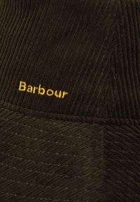 Zwarte corduroy pet met gestructureerde verticale strepen, voorzien van een gouden geborduurd "Barbour" logo aan de voorkant.
