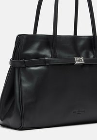 Czarna skórzana torebka o gładkiej fakturze, wyraźnym kształcie, podwójnych uchwytach i srebrnym akcentem na froncie.