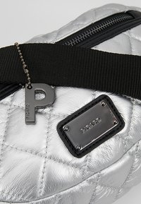 Sac argent matelassé avec fermeture éclair noire, sangle noire réglable, breloque métallique "P" et plaque métallique rectangulaire gravée "PICARD".