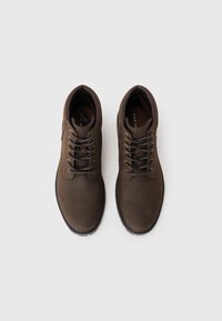 Zapatos de cuero marrón con puntas redondas, diseño de cordones, ojetes dorados y una suela de goma texturizada. El interior cuenta con una plantilla acolchada.