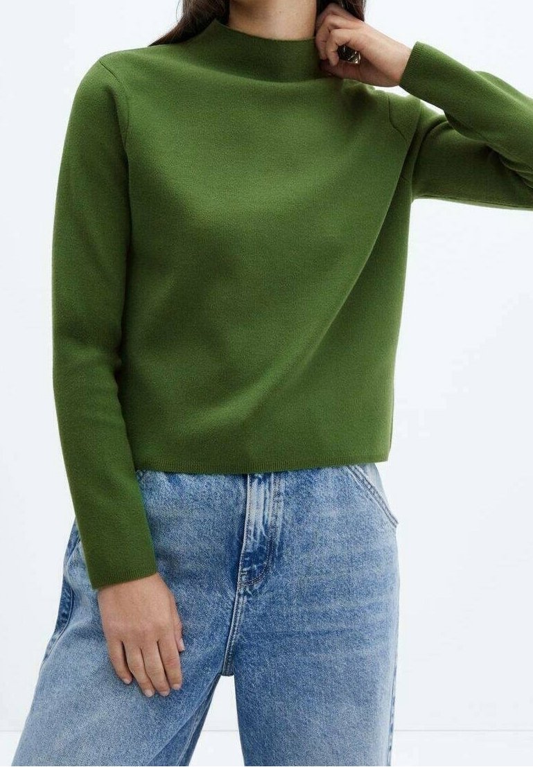 Pull en maille verte avec un col montant et des manches longues, assorti à un jean en denim bleu clair. Le tissu a une texture lisse.