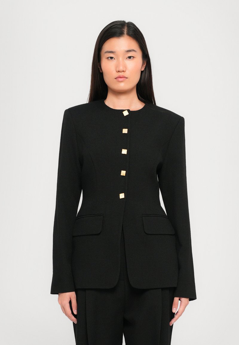 Zwarte op maat gemaakte blazer met een ronde halslijn, voorzakken en vijf vierkante goudkleurige knopen voor sluiting. Soepele textuur en gestructureerde pasvorm.
