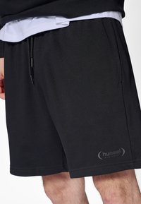 Schwarze Sportshorts mit elastischem Bund, Kordelzug und Hummel-Logo. Weicher Stoff und glatte Textur, mit Seitentaschen.