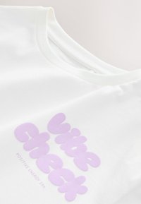 Fehér pamut póló nagy levendula grafikával, rajta a "Vibe Check" felirattal és alatta a "Pozitív Energia Kora" szöveggel.