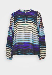 Blouse à manches longues avec des rayures horizontales en bleu, violet, noir et blanc, avec des volants aux épaules et aux poignets, et une patte de boutonnage à l'avant.
