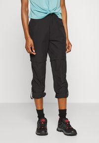 Svarta, lätta cargobyxor med justerbara benslut, framfickor och en avslappnad passform, kombinerat med en turkos kortärmad topp och svarta vandringsskor.