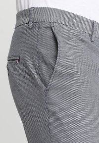 Herren-Hosen mit Muster in Grau mit einer Rautentextur. Verfügt über Seitentaschen, eine Gesäßtasche und kontrastierende Besatzakzente.