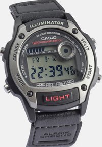 Digitális Casio óra fekete bőr pánttal, ezüst kiegészítőkkel és téglalap alakú óralappal. Tulajdonságai közé tartozik az ébresztő óra, a fénykapcsoló és az LCD kijelző, amely mutatja az időt.