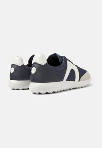 Navy and white sneakers featuring leather and suede materials, rounded toe, textured rubber sole, and a logo accent on the heel.