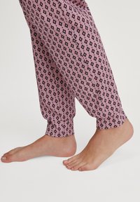 Roze gestreepte pyjamabroek met zwarte en blauwe diamantmotieven, elastische boorden en een relaxte pasvorm, met blote voeten.