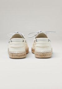 Espadrilles de cuero blanco con suela de yute tejido natural, con forma redondeada, parte delantera con cordones y ojales de metal.