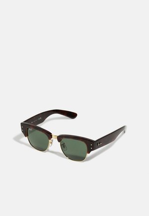 Occhiali da sole tartarugati marroni con lenti verde scuro, dotati di un accento in metallo dorato al ponte e una forma squadrata distintiva.