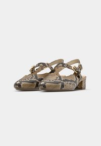 Low-heeled women's slingback shoes with beige and black snakeskin pattern and gold buckle closures on plain white background.