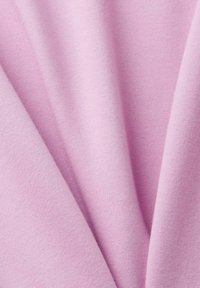 Tissu doux et texturé de couleur rose clair, présentant une surface lisse avec des plis subtils et un drapage, indiquant flexibilité et confort.