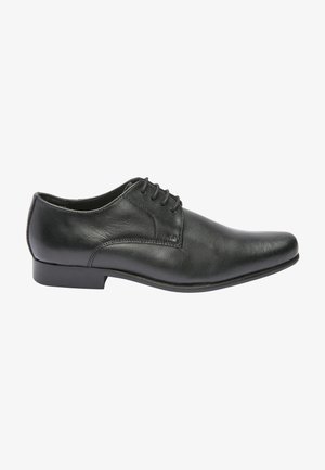 Chaussure habillée en cuir noir avec un bout arrondi, un design à lacets et une texture lisse. Elle possède un talon bas et plat avec des détails de couture simples.