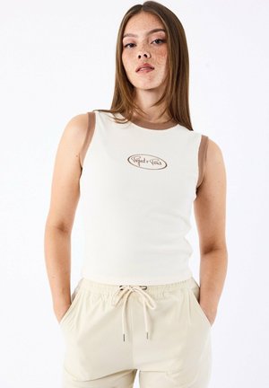 Débardeur côtelé en blanc cassé avec des accents marron et un logo brodé. Équipé de bretelles larges et d'une silhouette ajustée. Associé à un pantalon beige.