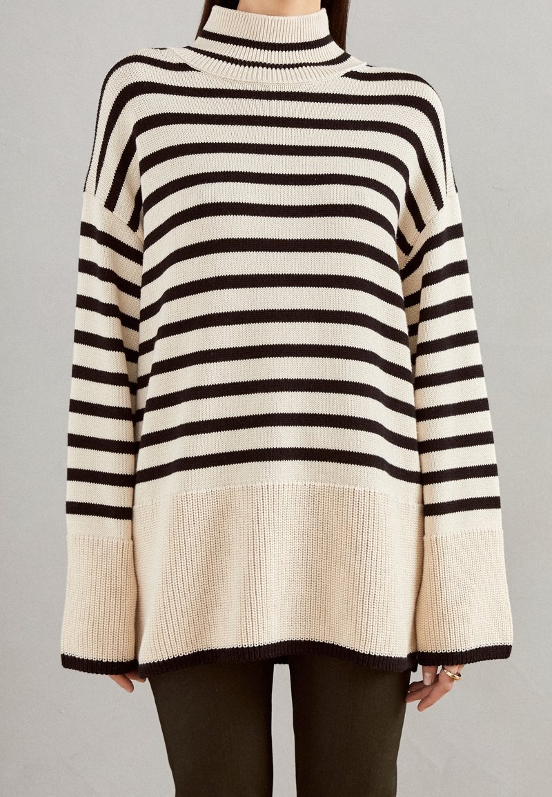 Sweter w paski w odcieniach kremowym i czarnym, z wysokim dekoltem, luźnym krojem, teksturowanym splotem oraz szerokimi rękawami zakończonymi ściągaczem u dołu.