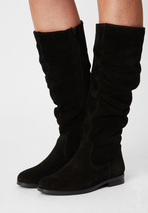 Stivali alti fino al ginocchio in camoscio nero con design morbido, cerniera laterale e tacco basso e robusto. Texture liscia con dettagli di cuciture minime.