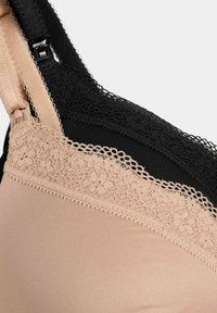 Soutien-gorge beige et noir avec accents en dentelle, tissu lisse, bretelles réglables et motif floral sur la bordure en dentelle le long des bords.