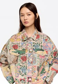 Chaqueta de patrón floral multicolor hecha de tela, con grandes bolsillos frontales, cierre de botones y un cuello estructurado.
