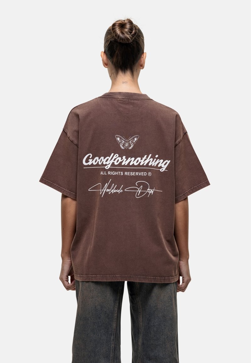 Brązowy, oversize t-shirt z krótkim rękawem. Posiada biały napis "Goodfornothing" oraz grafikę motyla na plecach. Teksturowana tkanina.