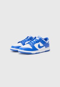 Blå og hvide Nike sneakers har en overdel i læder, perforeret tåboks og gummisål med blå accenter og snørebånd.