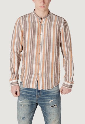 Camicia a maniche lunghe a righe nei toni beige, marrone e arancione, con colletto a bande e chiusura con bottoni, abbinata a jeans in denim strappati.