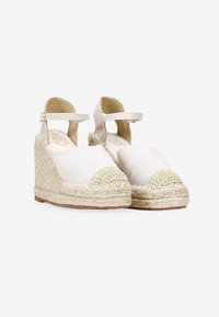 Escarpins compensés beige avec semelles en jute tressé, tige en toile et brides de cheville ajustables avec fermeture à crochet et boucle.