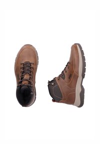 Brown leather hiking boots with textured fabric accents, lace-up design, rubber outsole, and padded collar. Features a sturdy build for durability.