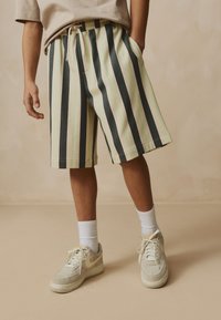 Gestreifte Shorts mit abwechselnden hellgrünen, beigen und dunkelgrauen Farben. Sie verfügen über einen elastischen Bund, seitliche Taschen und eine lockere Passform.