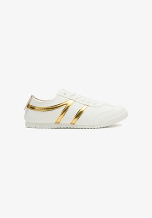 Zapatilla blanca de perfil bajo con rayas metálicas doradas, diseño con cordones y suela texturizada, vista lateral sobre fondo blanco.