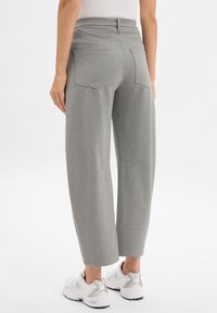 Gray wide-leg pants with a high waistband, two rear pockets, and a smooth texture, paired with white athletic shoes.