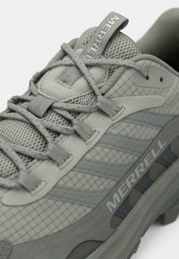 Γκρι πεζοπορικό παπούτσι που συνδυάζει υφή σουέντ και δίχτυ. Σημαντικές λεπτομέρειες περιλαμβάνουν ριγέ διακοσμητικά και ενισχυμένη μύτη.