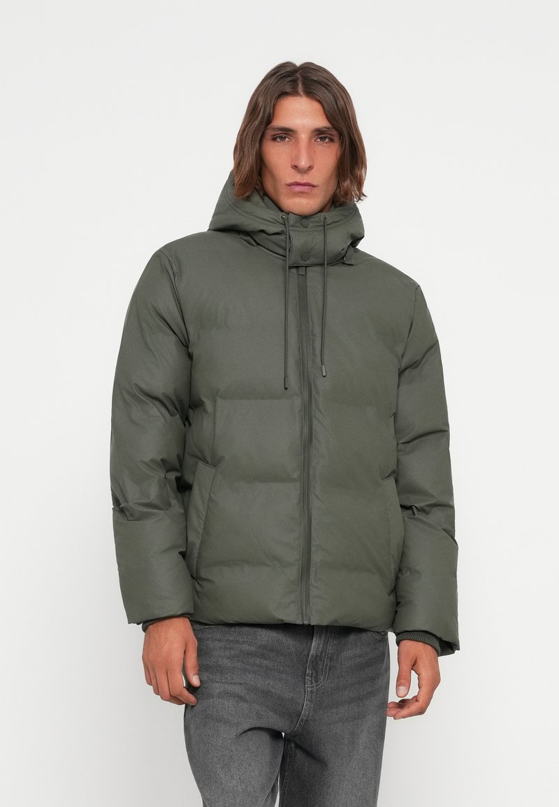 Green puffer jacket with a hood, featuring a zippered front, adjustable drawstrings, and a quilted texture. Paired with dark jeans.