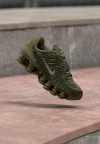 Nike-sneaker i olivengrøn, med mesh og syntetiske materialer, slankt design, hævet gummisål og en tekstureret overflade.