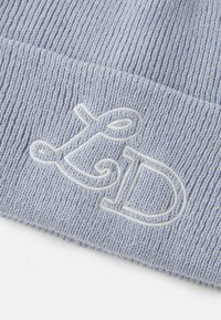 Beanie lavorato a maglia di colore blu chiaro con texture a coste e un logo bianco ricamato con lettere intrecciate sul davanti.