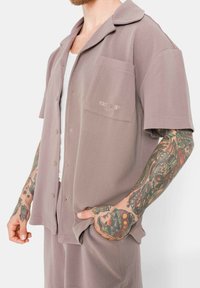 Kurzärmliges, knöpfbares Hemd aus weichem, strukturiertem Mauve-Stoff, mit einer Brusttasche und gesticktem Logodetail.