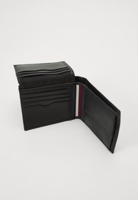 Portafoglio in pelle nera con più scomparti per carte, texture liscia e un accento a strisce tricolori all'interno. Design pieghevole, forma compatta.